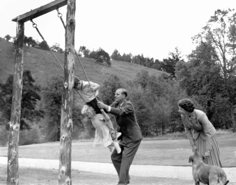 Prince Charles and Princess Anne pushed on a swing by the Duke of Edinburgh, watched by Queen Elizabeth II at Balmoral in 1955.