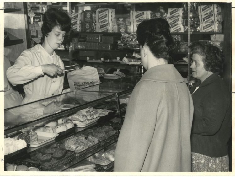 Linda Sim, an Aberdeen shop assistant, uses tongs when serving customers in a West End baker's shop.