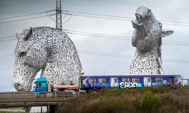 One of the hydrogen train carriages passing the Kelpies in Falkirk.