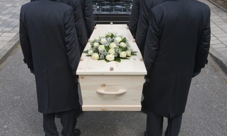Bearers a carrying a coffin into a car