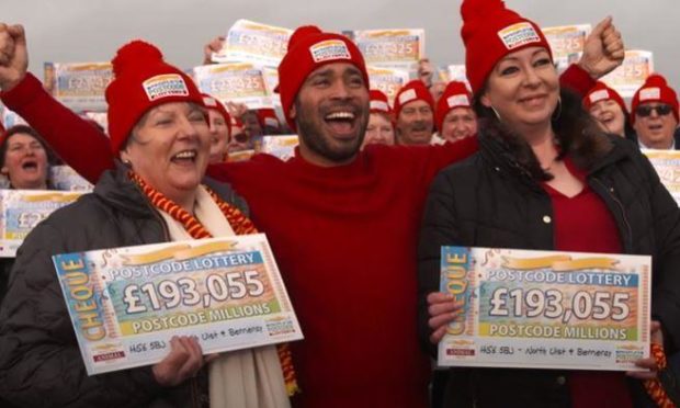 Sharon MacKillop, People's Postcode Lottery ambassador Danyl Johnson and Pamela Macaskill celebrate the win at Carinish Village Hall, North Uist. Supplied by Postcode Lottery/Youtube