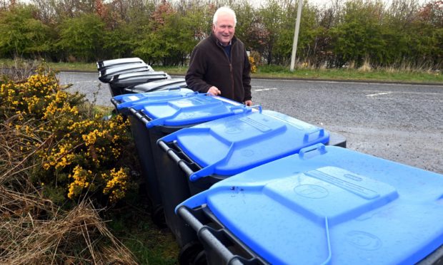 CR0028011 Councillor Colin Pike has claimed that Aberdeenshire Council are trying to sneak plans through the back door which would mean residents' bins are collected every three weeks, rather than two. Councillor Pike is pictured with household bins in Lairhillock which shows how dysfunctional the bin collection already is, even before the mooted changes.