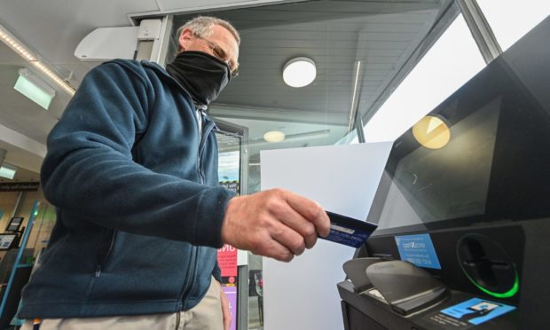 Cullen Community Council member Colin Burch uses the new cash machine at the Co-op.