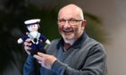 Howard Drysdale smiling and holding a knitted sailor toy.