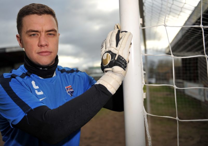 Michael Fraser in his Ross County kit, gloved hands on the goal post