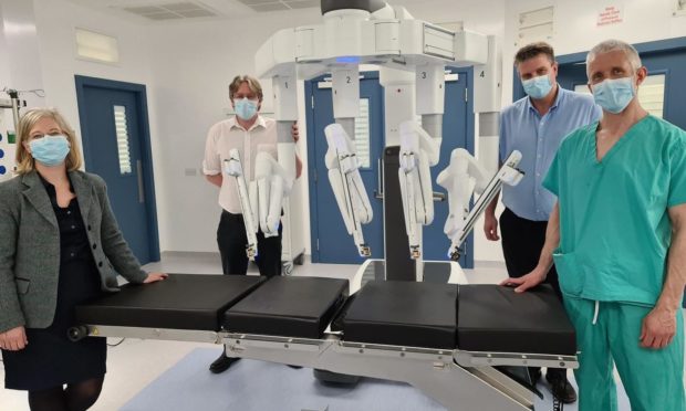 Emma Watson, Deputy Medical Director (Acute); Alan Grant. Clinical Director for Surgery, Anaesthesia and Critical Care; Kenny Oliver, Service Manager for Theatres; and Colin Richards, Consultant Colorectal Surgeon next to DaVinci Xi