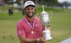 Jon Rahm, of Spain, holds the champions trophy after winning the US Open