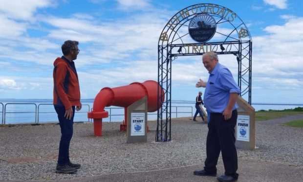 Walter Mowat, from John O'Groats Development Trust, shows off the new archway to a tourist