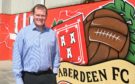 Aberdeen's commercial director Rob Wicks in front of some of the new artwork at Pittodrie