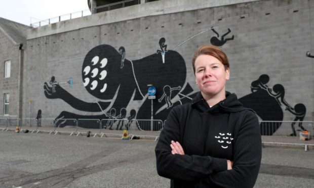 Artist KMG (Katie Guthrie) pictured with her striking mural on Palmerston Road