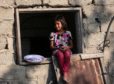 A Palestinian girl sits at the window of a house during hot weather near Khan Younis refugee camp in southern Gaza Strip, on June 29, 2021.