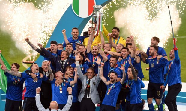 Captain Giorgio Chiellini lifts the trophy as Italy players and coach Robert Mancini celebrate  winning Euro 2020.
