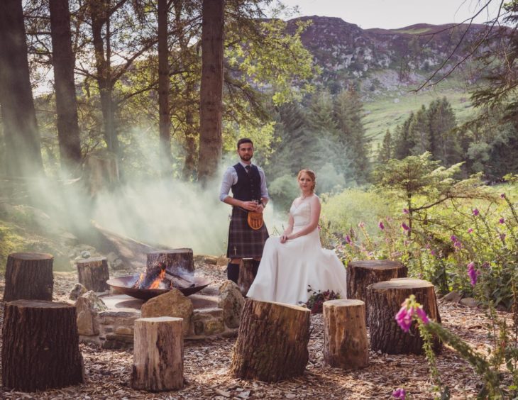 A bridge and groom sitting near a fire at one of Scotland's more unusual wedding venues