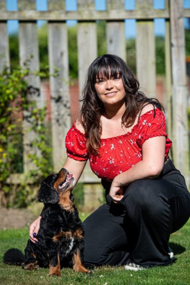 Toni Gordon kneeling down in a garden with her dog