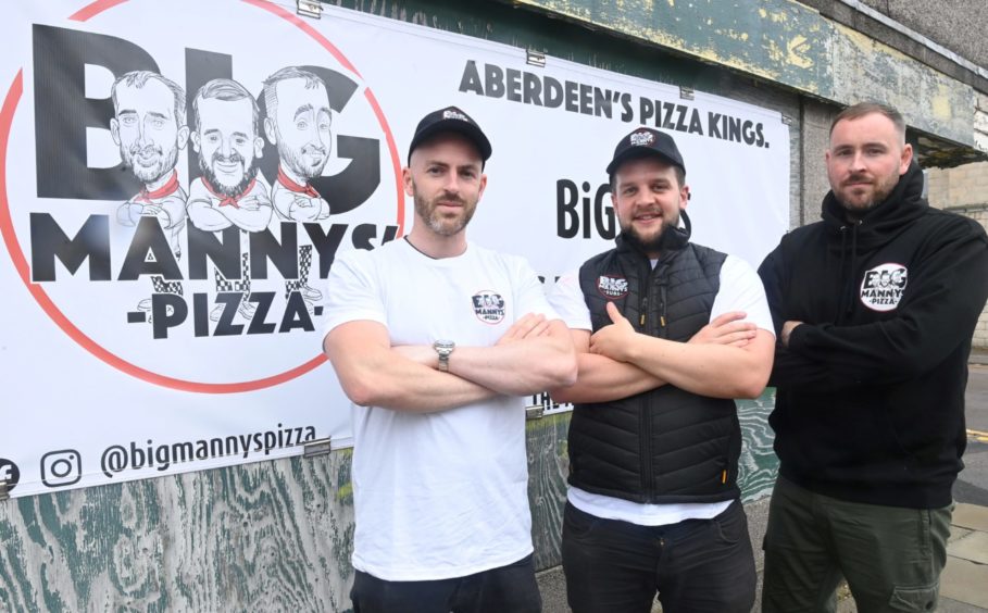 Philip Adams, Calum Wright and Ashley Adams from Big Manny's Pizza in front of business banner