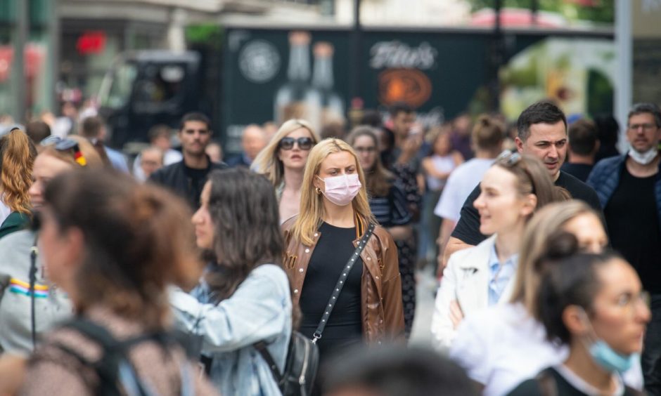 A woman wearing a face mask among a crowd of pedestrians.