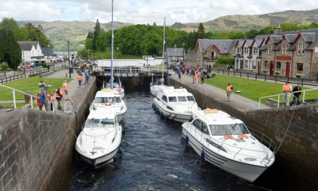 Visitors watch yachts climb the locks of the Caledonian Canal at Fort Augustus.