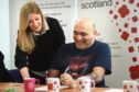 A man being helped by a staff member of Poppyscotland