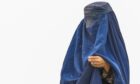 An Afghan burqa-clad woman from northern provinces stands near her shelter after she fled from her home due to the fighting between Taliban and Afghan security forces. Shutterstock
