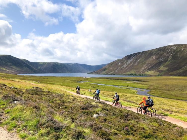 Group of people riding bicycles near Lochnagar. Airbnb is helping tourism recovery Scotland.