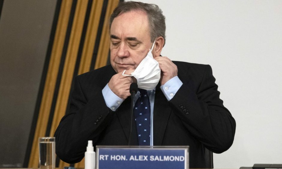 Former first minister Alex Salmond removes a face mask before giving evidence to a Scottish Parliament Harassment committee