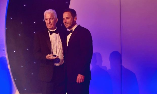 Peter Gray, joint managing director of Gray & Adams, left, accepts the lifetime achievement gong for his father from Scott Dargan, of award sponsor Carrier Transicold UK, amid a standing ovation for the north-east company's late founder, Jim Gray.