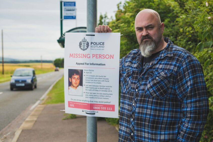 Charlie Reid beside a missing person poster asking for information about his son Shaun Ritchie who disappeared on October 31, 2014. 