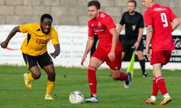 Lossiemouth's Ryan Stuart, centre, looks to get away from a Fort William player