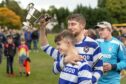 Newtonmore captain Sorley Thomson goes to share the Sutherland Cup with his team.