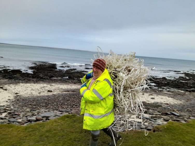 Dorcas Sinclair from Caithness Beach Cleans carrying a huge wad of plastic 