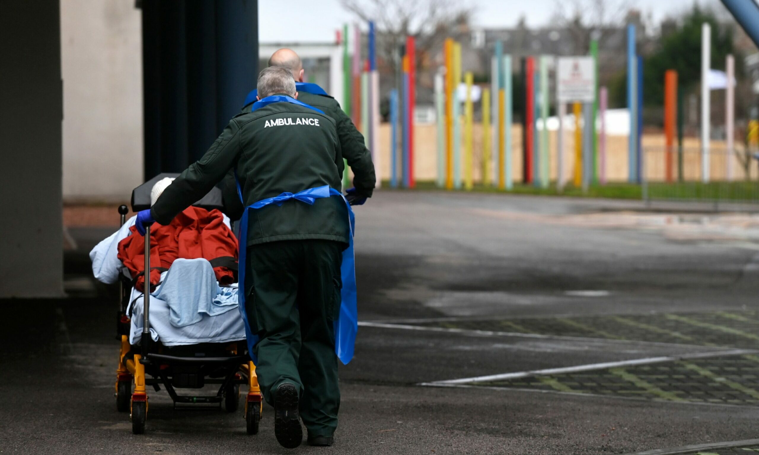 An ambulance technician pushes a patient in a wheelchair outside Aberdeen Royal Infirmary