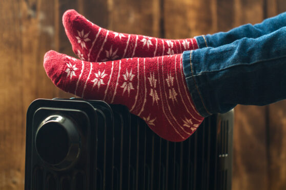 someone with their feet on a radiator - using heating oil in winter to stay warm