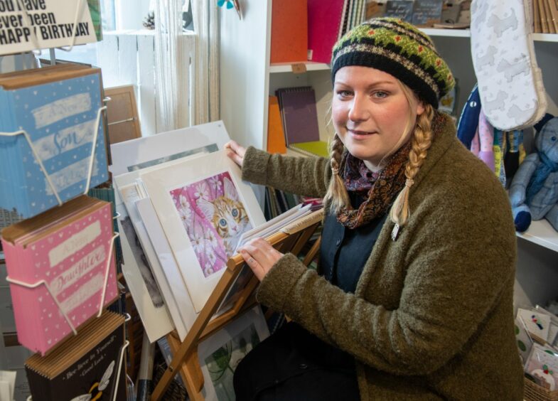 Jodie sitting and flicking through a magazine rack of paintings