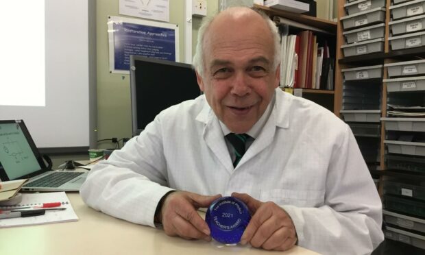 Stephen Dempsey in a white coat holding his paperweight award
