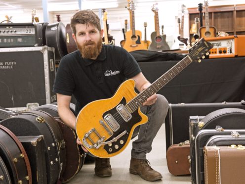 Auctioneer Luke Hobbs with George Harrison’s Maton guitar (Gardiner Houlgate/PA)