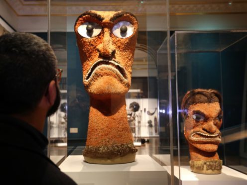 A visitor looks at two examples of Akua Hulu Manu, feathered god images, during a press view for Oceania at the Royal Academy (Jonathan Brady/PA)