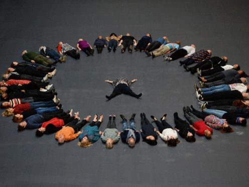 Artist Tania Bruguera, centre, and guests lie on her artwork Hyundai Commission, a heat sensitive floor, in the Turbine Hall, Tate Modern (Kirsty O’Connor/PA)
