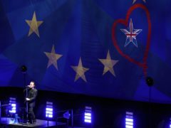 U2’s Bono performs in front of a giant flag (Andrew Matthews/PA)