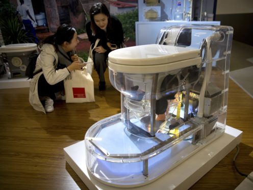 Visitors look at a model of a self-contained toilet at the Reinvented Toilet Expo in Beijing (Mark Schiefelbein/AP)