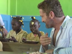 Gerard Butler shares a meal with children in Haiti (Mary’s Meals/PA)