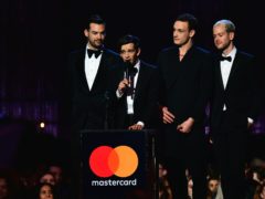 Matt Healy (centre) of the The 1975 accepts a Brit award (PA)