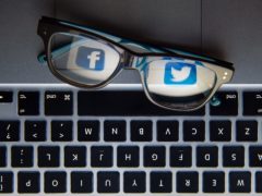 The logos of social network sites Facebook and Twitter reflected in a pair of glasses.