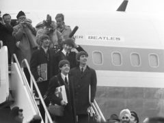 The Beatles pause to look at the huge crowds after their return from the US in 1964 (PA)