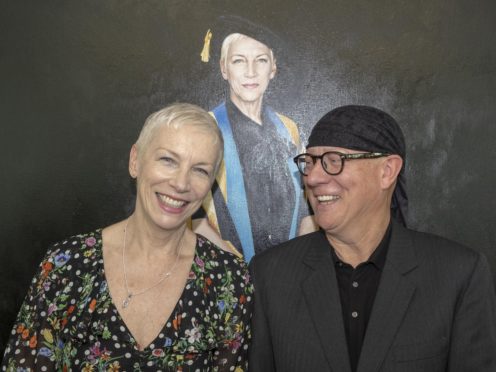 Annie Lennox with artist Gerard Burns (right) in front of the portrait (GCU/PA)