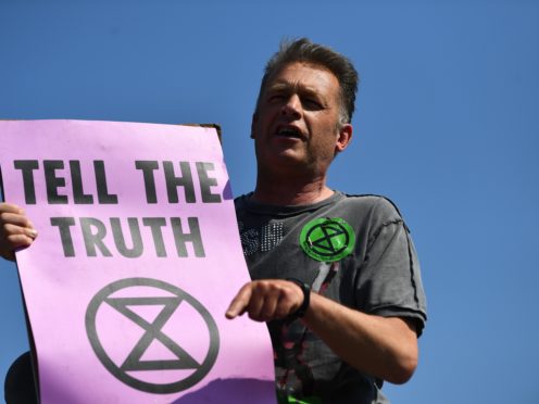Chris Packham makes a speech on top of a bus stop during an Extinction Rebellion demonstration. (Victoria Jones/PA)