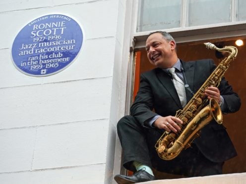 Alex Garnett posing with Ronnie Scott?’s tenor saxophone at the site of his newly unveiled English Heritage Blue Plaque (English Heritage/Jed Leicester/PinPep/PA)