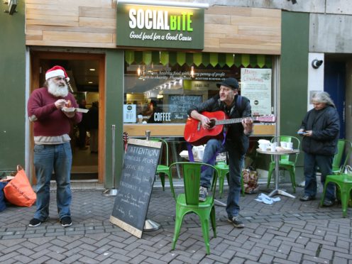 Homeless man David Roberts (left) receiving a free Christmas meal from Alice Thompson and Josh Littlejohn from the Social Bite sandwich bar in Edinburgh (Andrew Milligan/PA)