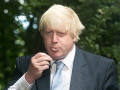 Boris Johnson eats bread cooked on a bonfire using sticks in 2015 (PA)