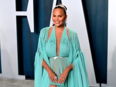 Chrissy Teigen has revealed she is torn about undergoing further breast surgery due to fears of complications on the operating table (Ian West/PA)