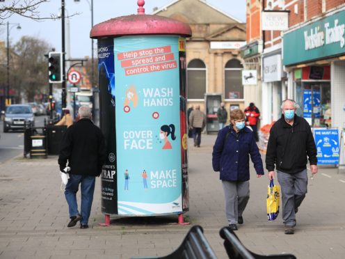 People wearing face masks walk past a coronavirus advice sign in Skegness, Lincolnshire (Mike Egerton/PA)